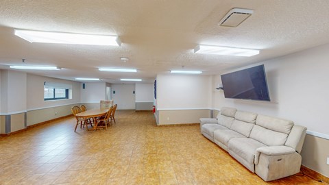 A living room with a couch, chairs, and a television.