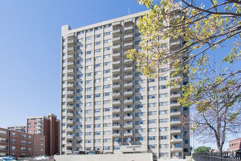 a tall apartment building with many windows and a tree