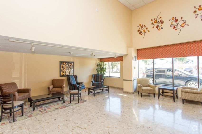 a lobby with chairs and a table and a large window