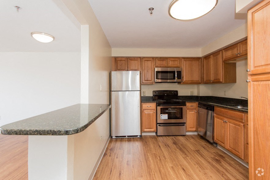 an empty kitchen with wooden cabinets and stainless steel appliances