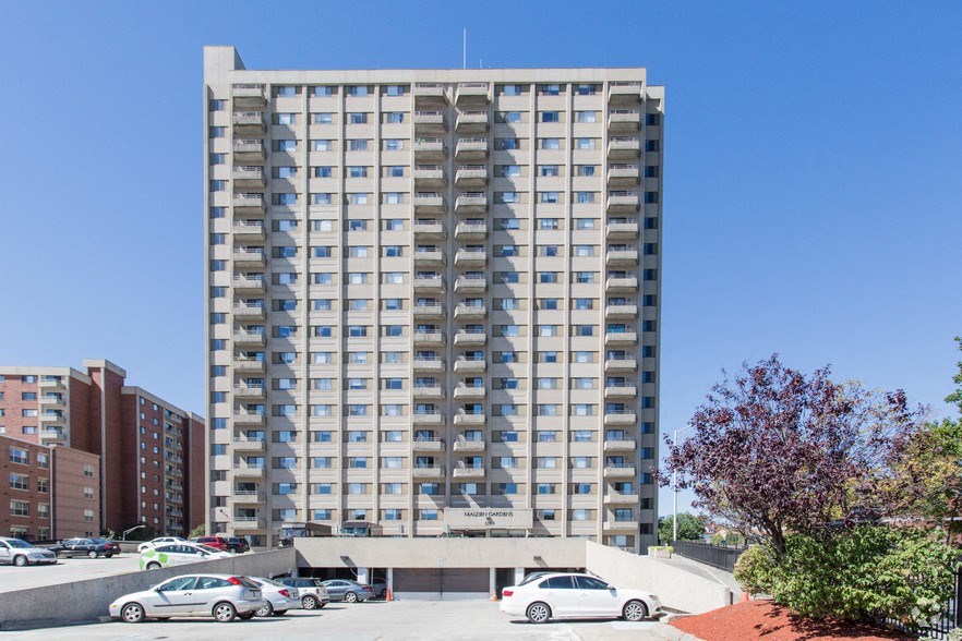 a tall apartment building with cars parked in a parking lot