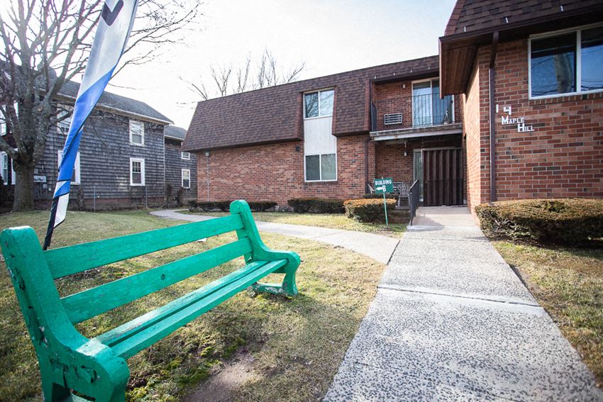 a green bench in front of a brick building