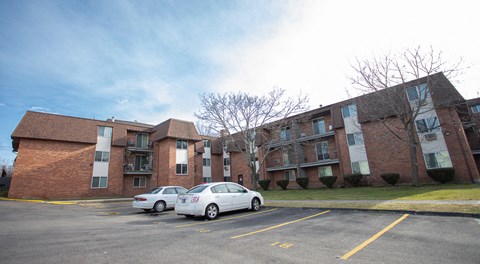 a large brick apartment building with two cars parked in front