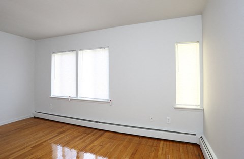 an empty room with wooden floors and two windows