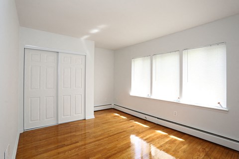 an empty bedroom with white walls and wood floors