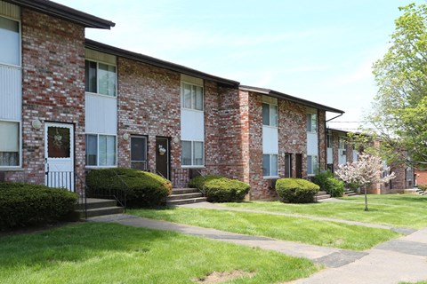 a row of brick apartment buildings with a sidewalk and grass