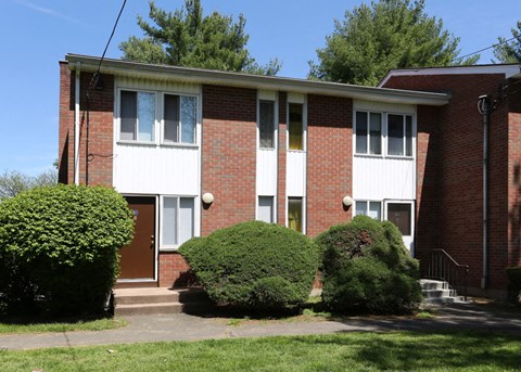 a red brick building with three bushes in front of it