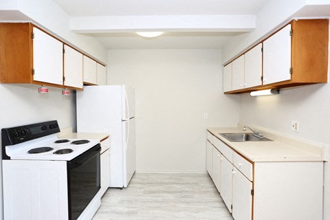 an empty kitchen with white appliances and white cabinets