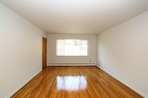 an empty room with wooden floors and a window