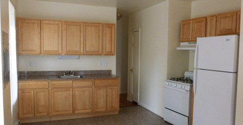 an empty kitchen with white appliances and wooden cabinets