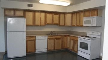 an empty kitchen with white appliances and wooden cabinets