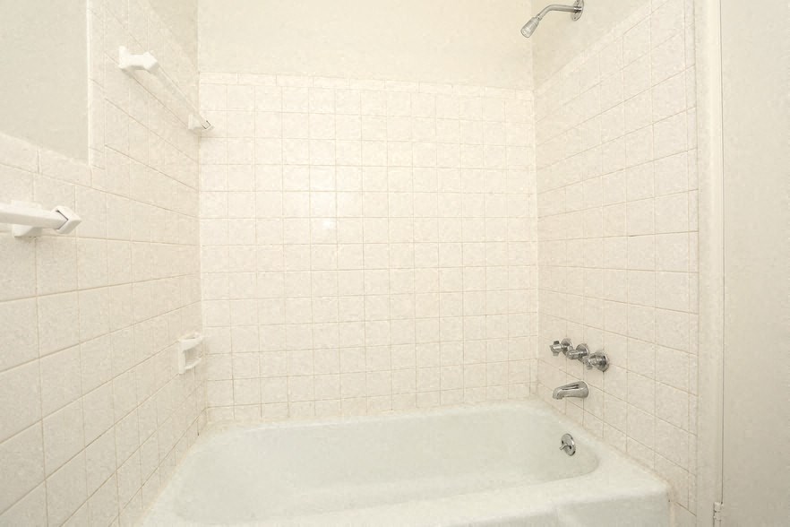 a white bath tub in a white tiled bathroom