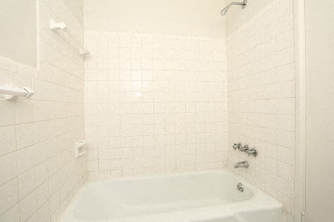 a white bath tub in a white tiled bathroom