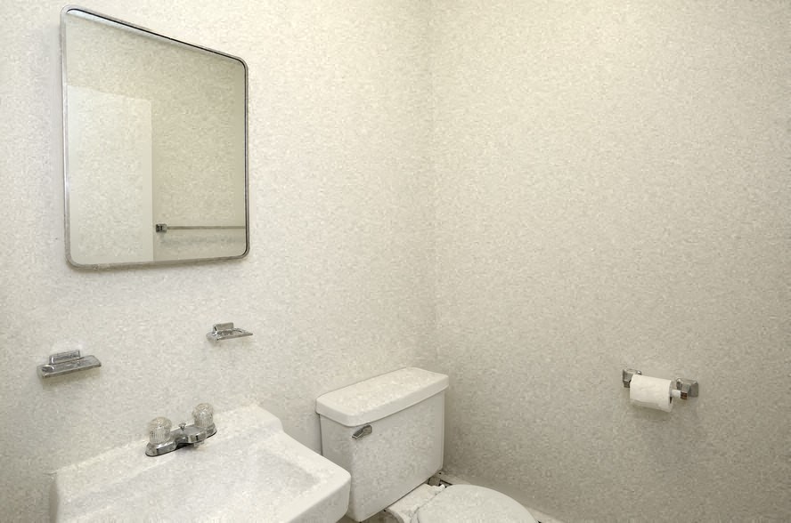 a white bathroom with a mirror and a toilet and a sink