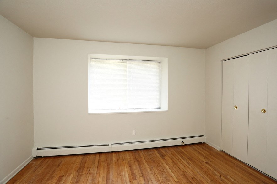 a bedroom with white walls and a window and wooden floors