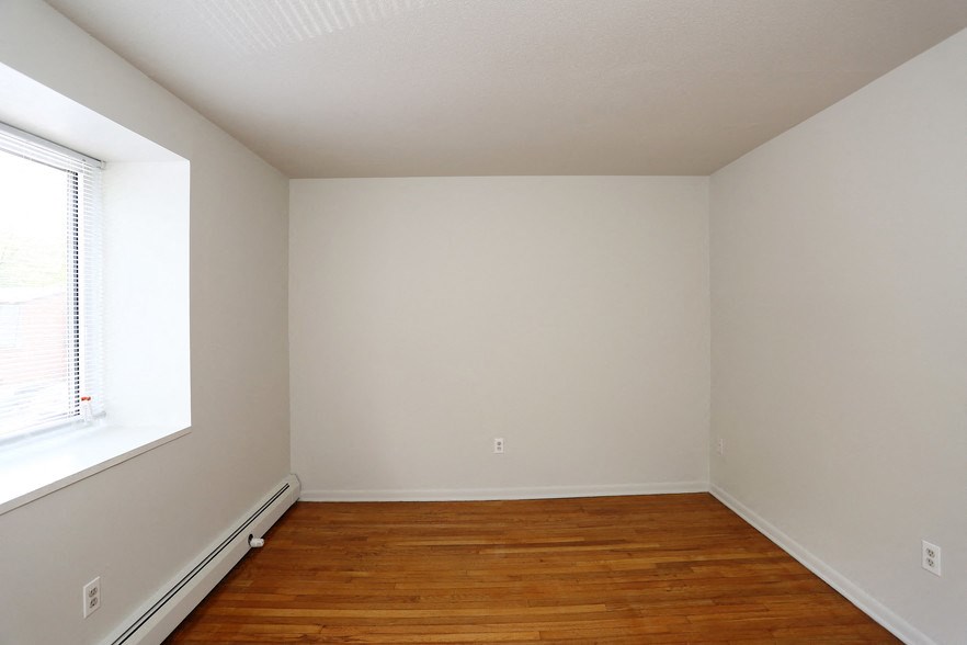 an empty room with wooden floors and a window