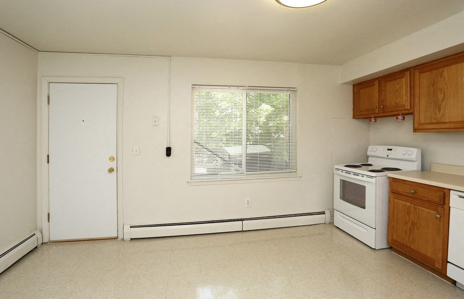 an empty kitchen with white appliances and wooden cabinets