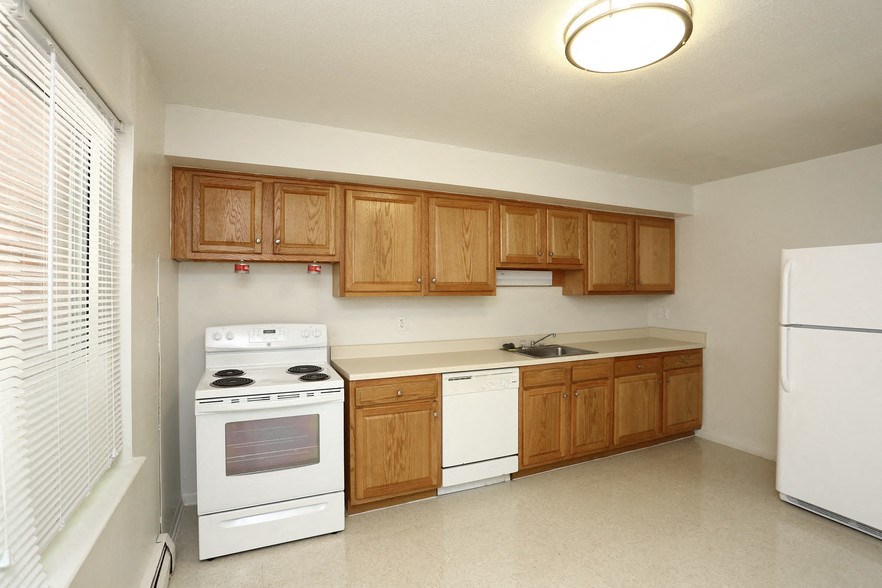 an empty kitchen with white appliances and wooden cabinets