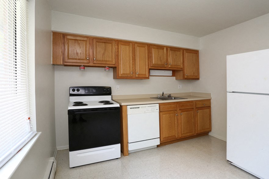 an empty kitchen with white appliances and wooden cabinets