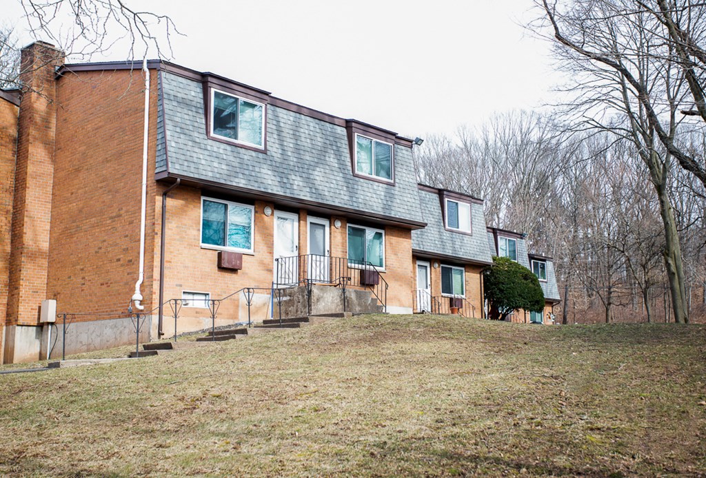 the exterior of a brick house with green shutters and a yard