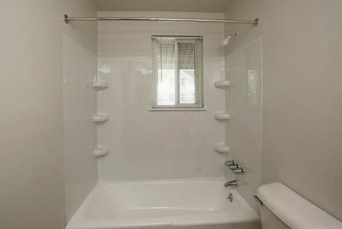 a white bathroom with a tub and a window
