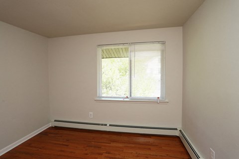 a bedroom with a window and wooden floors