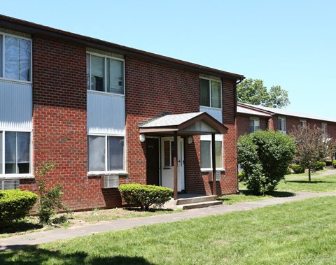 a brick apartment building with a sidewalk in front of it