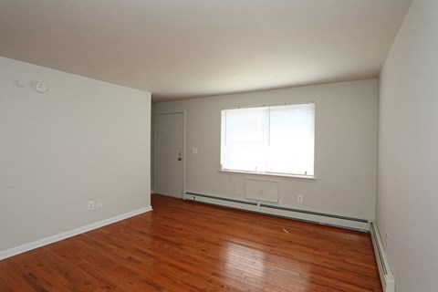 an empty living room with wood floors and a window