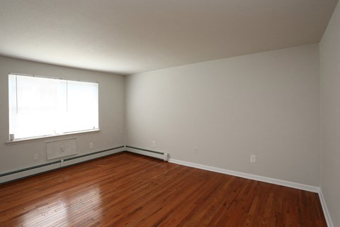 an empty room with wooden floors and a window