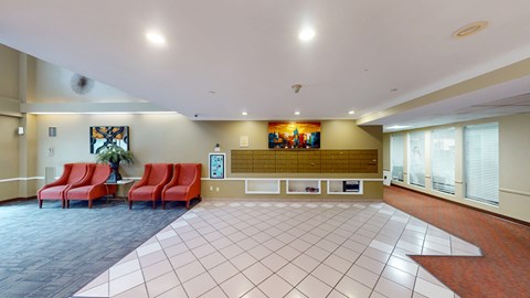 A spacious waiting area with red chairs and a large painting on the wall.