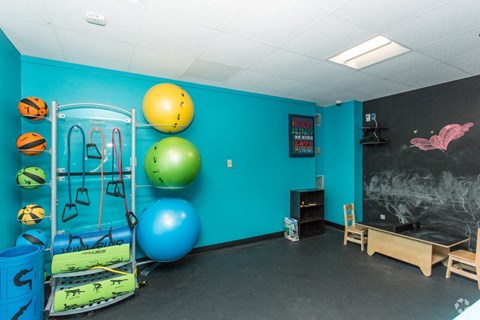 a room with a chalkboard and a gym with balls and other equipment