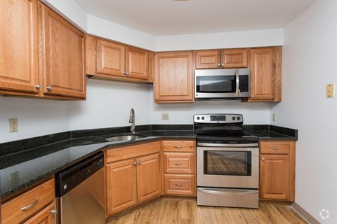 an empty kitchen with wooden cabinets and stainless steel appliances