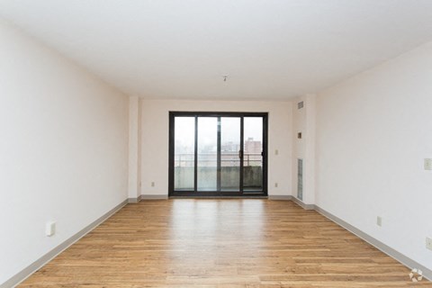 an empty living room with white walls and a sliding glass door