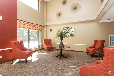 a lobby with red chairs and a table and a large window
