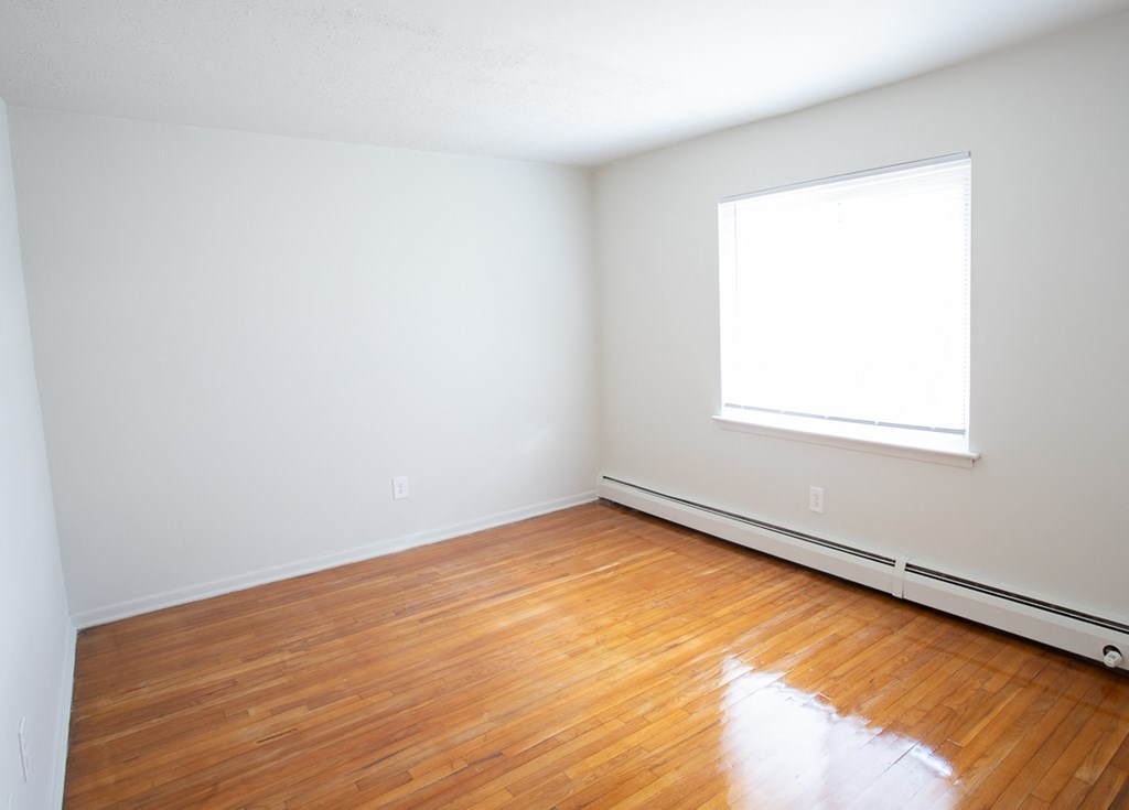 an empty room with wood floors and a window