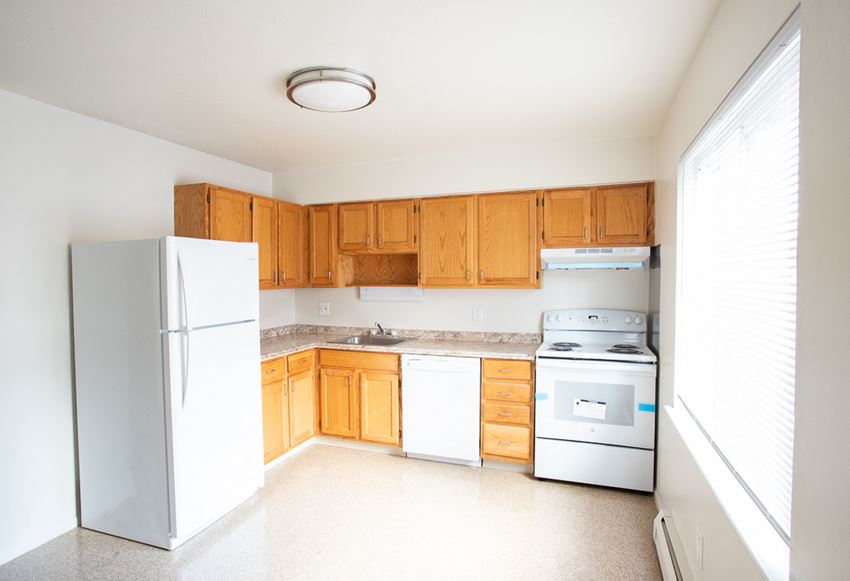 an empty kitchen with white appliances and wooden cabinets