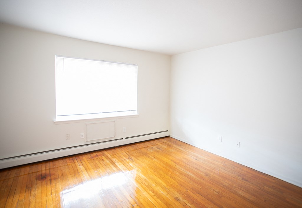 an empty room with wood floors and a window