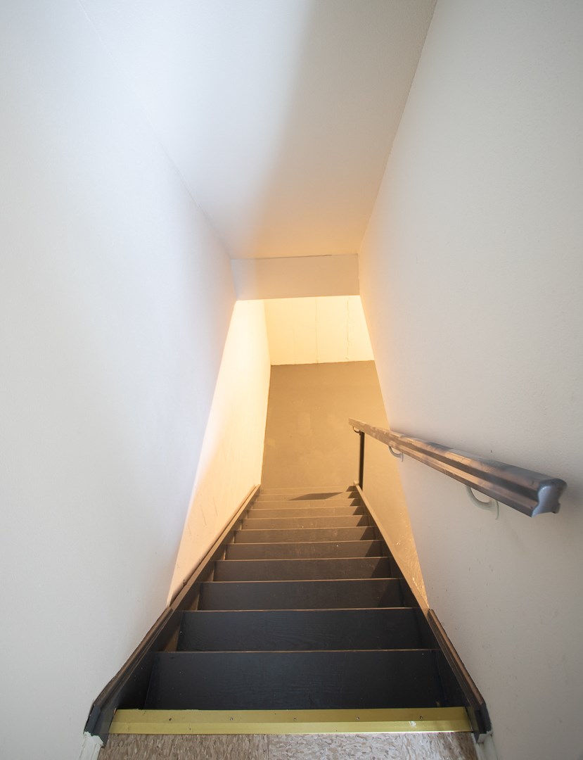 a stairwell with a rail and a staircase with a black staircase