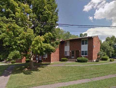 a red brick house with a tree in front of it