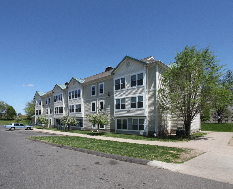 a row of apartment buildings on a street with a car