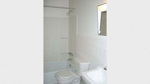 a white bathroom with a toilet and a bath tub