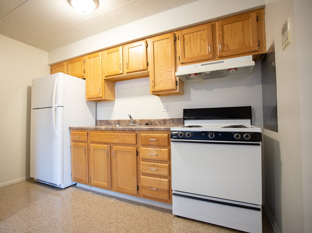 an empty kitchen with white appliances and wooden cabinets