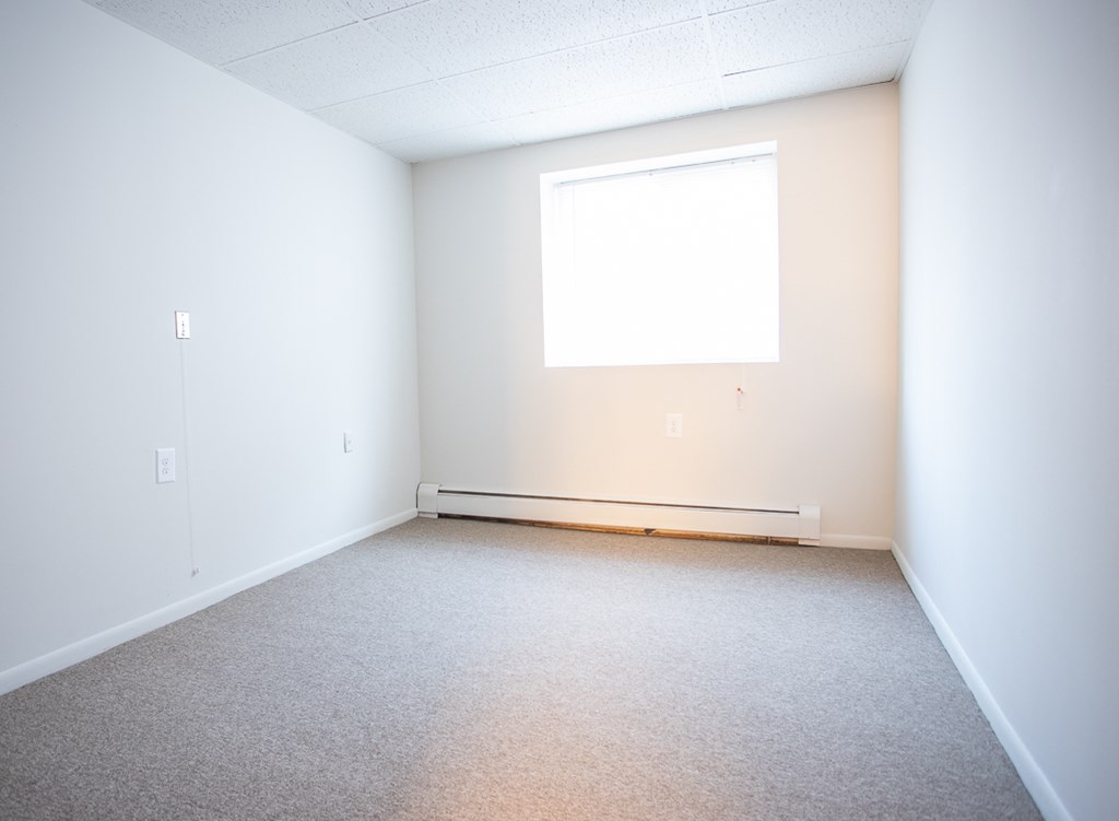 an empty room with white walls and a window