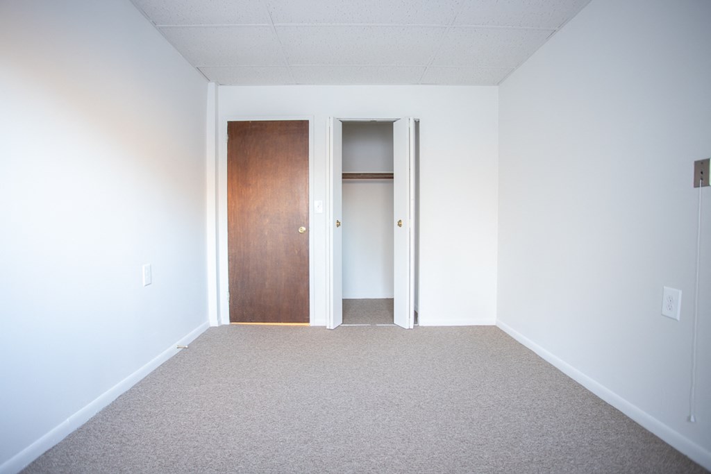 an empty room with a carpet and a door to a closet