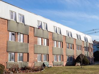 a brick building with a white roof and a grid of windows