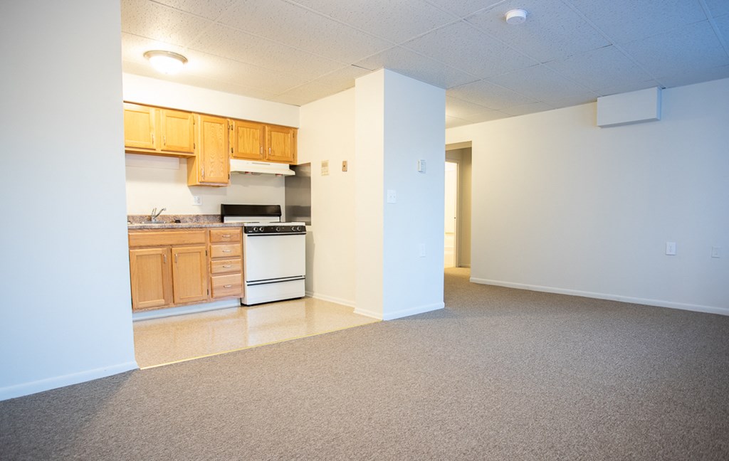 an empty kitchen with white appliances and wooden cabinets