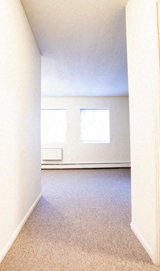 an empty room with two windows and a carpeted floor