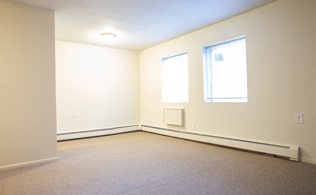 an empty room with two windows and a carpeted floor