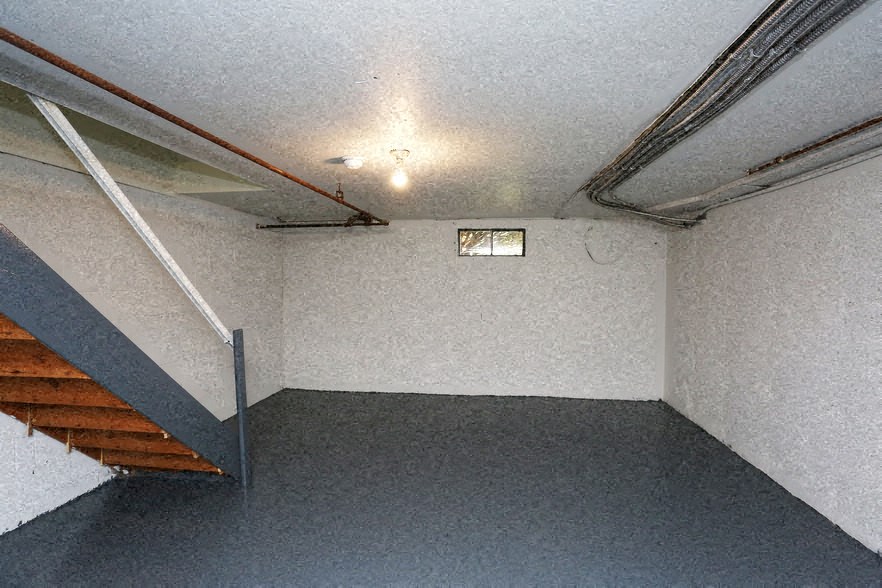 an empty basement with stairs and a window