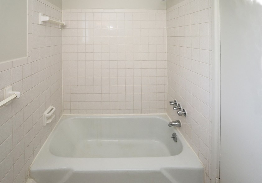 a white bath tub in a white tiled bathroom